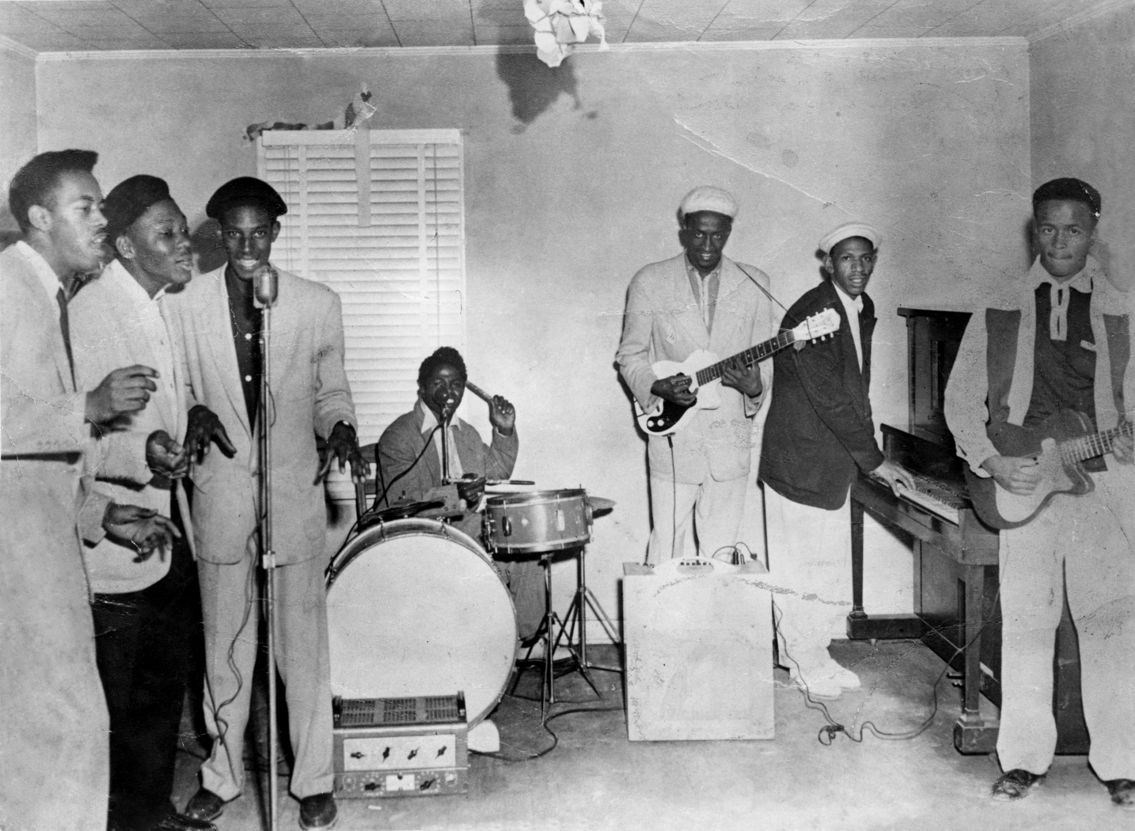 James Brown and the Original Flames, 1956. (left to right) Sylvester Keels, Nash Knox, Fred Pulliam, James Brown (on drums), Nafloyd Scott, Bobby Byrd (on piano), and Roy Scott. Photo via Michael Ochs Archives/Getty Images.